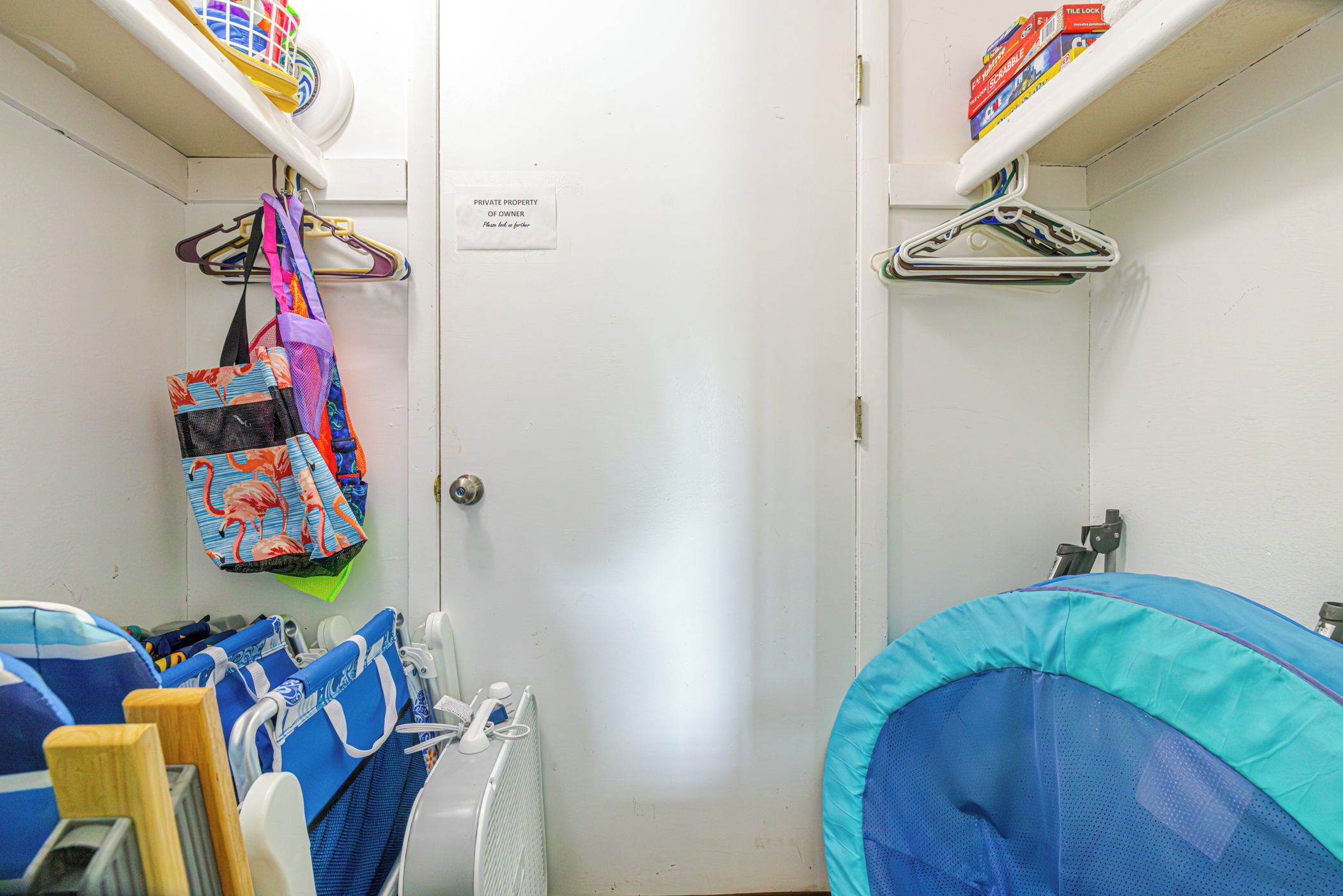 Casa de banho privativa com sanita, área de duche e prateleira com cabides e um saco.