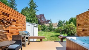 Een terras buiten met een barbecue, zitplaatsen en een hottub.