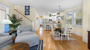 A spacious living room with a grey sofa, a wooden coffee table, and a dining area with white chairs and a wooden table. - Seagrove Beach - Private Heated Pool - Bikes (Santa Rosa Beach)