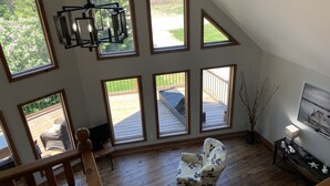 Una stanza spaziosa con diverse finestre a lucernario, un pavimento in legno, un'ampia vetrata e vista su terrazza e giardino.