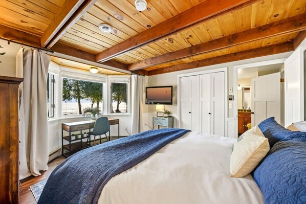 A bedroom with a large bed, a desk, and a TV.