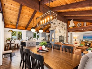 Amplia sala de estar con mesa de comedor de madera, varias sillas y chimenea de piedra.