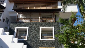 A multi-story building with a stone facade, balconies with wooden railings, and windows with white frames. - Charming Dominicus Bayahibe Apartment 2 bedrooms (Dominicus, Bayahibe)