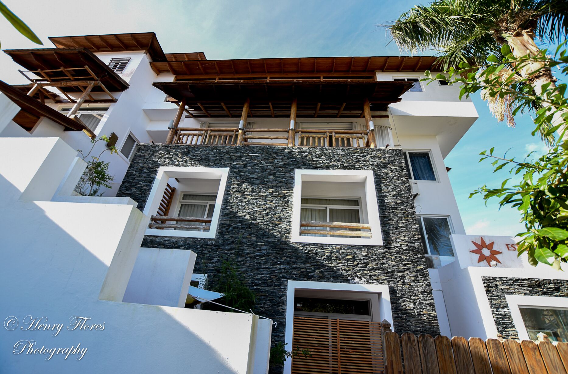A modern building with a stone facade, multiple balconies, and a wooden pergola.