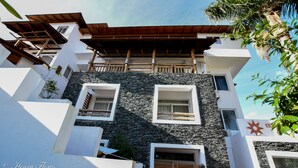 A modern building with a stone facade, multiple balconies, and a wooden pergola. - Charming Dominicus Bayahibe Apartment 2 bedrooms (Dominicus, Bayahibe)
