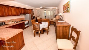 A compact kitchen with wooden cabinets, a dining table with chairs, a refrigerator, and a microwave. - Charming Dominicus Bayahibe Apartment 2 bedrooms (Dominicus, Bayahibe)