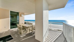 A balcony with a table and chairs, overlooking a beach. - 🌊Beachfront-Balcony-5 Pools-Majestic Beach 1-301🌊 (Panama City Beach)