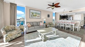A spacious living room with a grey sofa, a patterned armchair, a coffee table, and a dining area with a white table and chairs. - 🌊Beachfront-Balcony-5 Pools-Majestic Beach 1-301🌊 (Panama City Beach)