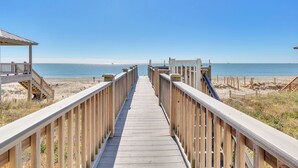 Ein hölzerner Steg führt zu einem Strand mit freiem Blick auf den Ozean.