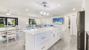 A modern kitchen with a central island, white cabinetry, and a stainless steel refrigerator.