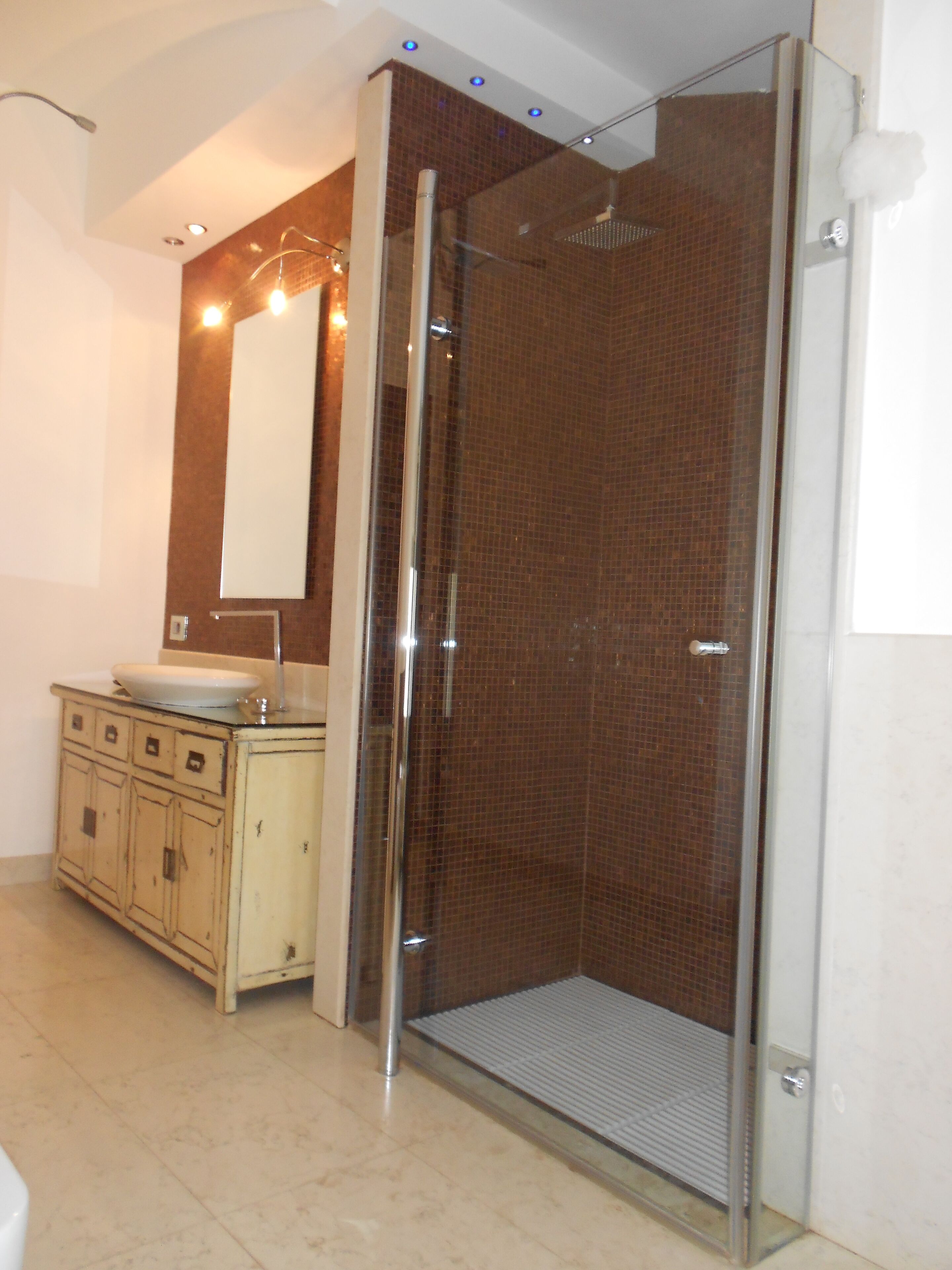 Une salle de bain avec une douche à parois de verre, un lavabo et un meuble de rangement.