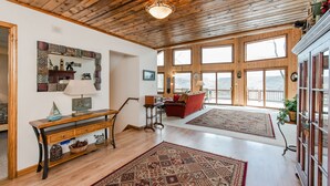 A spacious living room with wooden floors, a large mirror, a wooden console table, and a red sofa.