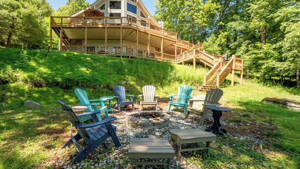 A cabin with a deck, outdoor seating, and a fire pit.