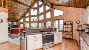 A spacious kitchen with wooden walls, large windows, and a central island.