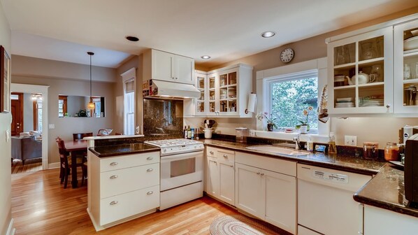 A modern kitchen with white cabinetry, a central island, and a window providing natural light.