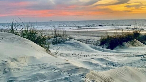 Una platja amb dunes de sorra i un capvespre.