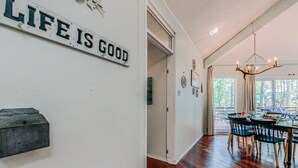 Un comedor con una mesa y sillas de madera, una lámpara de araña y un cartel en la pared que dice "LIFE IS GOOD".