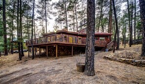 A cabin with a wooden deck, surrounded by tall pine trees. - Cedarside Cabin K9 Friendly | Pine-Scented Getaway w/ Hot Tub & Wraparound Deck (Ruidoso)