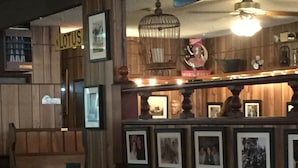 A restaurant interior with wooden walls, framed pictures, and a 'LOTUS' sign. Tables are set with chairs and tableware. - OCEAN BREEZE BEACH HOME (Oxnard)