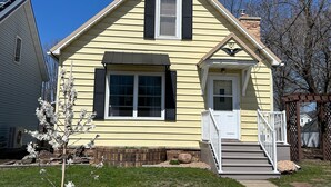 Une maison à deux étages avec un porche à l’avant, une cheminée et une boîte aux lettres.