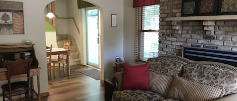Una sala de estar acogedora con chimenea, piso de madera, un sofá y un comedor con mesa y sillas.