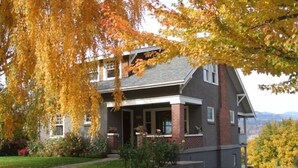 A two-story house with a porch, brick foundation, and a view of the surrounding landscape.