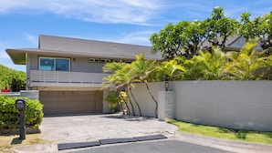 A two-story residential building with a garage, a driveway, and a small garden area with palm trees. - Pueohala: Spectacular Kailua Beachfront - updated Beach House (Kailua)