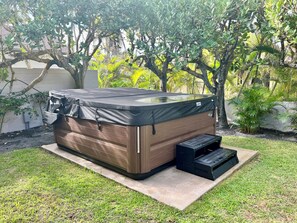 Uma banheira de hidromassagem num jardim, com degraus que a levam.