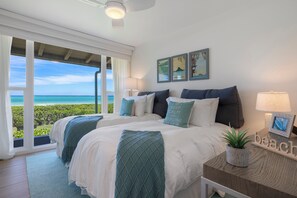 Une chambre avec deux lits, une vue sur l’océan et une décoration sur le thème de la plage.