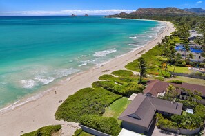 A coastal property with a beachfront, lush greenery, and a clear view of the ocean.