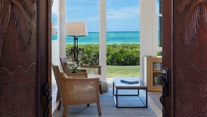 A room with a view of the ocean, a chandelier, and a wooden door with leaf carvings. - Pueohala: Spectacular Kailua Beachfront - updated Beach House (Kailua)