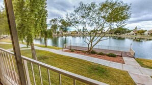 Une vue d’un lac avec une terrasse en bois et une zone herbeuse au premier plan.