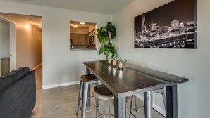Uma cozinha moderna com área de refeições, um quadro de paisagem urbana e uma escada que leva a outro cômodo.