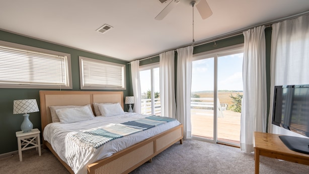 A bedroom with a large bed, a TV, and a view of the outdoors.