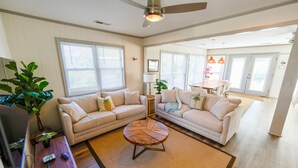 A living room with two beige sofas, a wooden coffee table, and a ceiling fan.