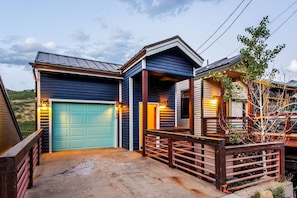 A two-story house with a blue garage door, a covered porch, and a wooden fence. - 5BR Old Town Home + Hot Tub | Walk to PCM Base & Main Street (Park City)