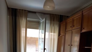 Een kamer met een ronde tafel, vier stoelen, een potplant en een garderobe.