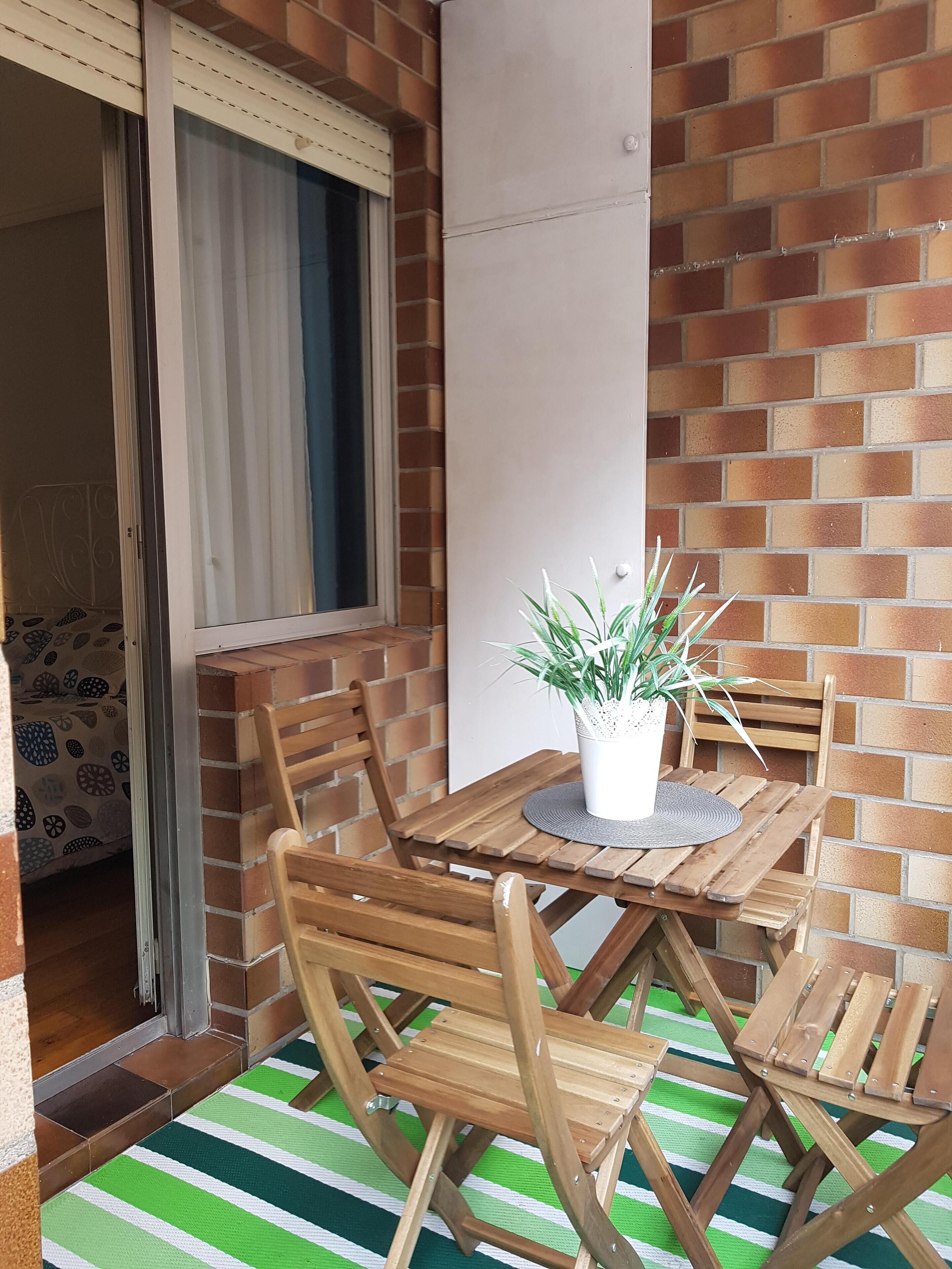 A wooden table and chairs set on a green and white striped mat, with a potted plant on the table.