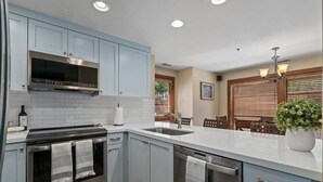 A modern kitchen with light blue cabinets, stainless steel appliances, and a white countertop. - The Silver Cliff, 2BR Walk to Lifts and Main St! (Park City)