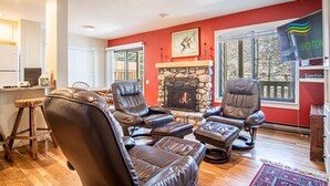 A living room with leather recliners, a stone fireplace, and a large window. - SV115 - Walk to Lifts & Town - Hot Tub & Pool (Ketchum)