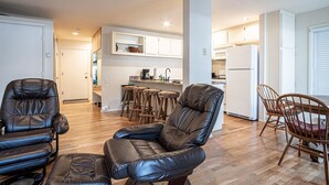A modern living room with leather chairs, a wooden dining table, and a kitchen in the background. - SV115 - Walk to Lifts & Town - Hot Tub & Pool (Ketchum)