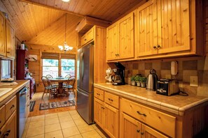 Une cuisine rustique, située dans une cabane en bois, avec un îlot central, un réfrigérateur et une machine à café.