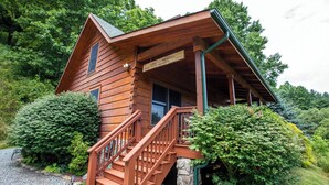 Una cabaña de madera con un porche, una escalera y un letrero que dice "Mountain Meadows".
