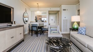 Une chambre d’hôtel moderne dotée d’un coin repas, d’un canapé, d’une télévision et d’un ventilateur de plafond.