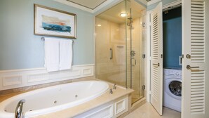 Une salle de bain avec une grande baignoire, une douche à parois de verre et un lave-linge.