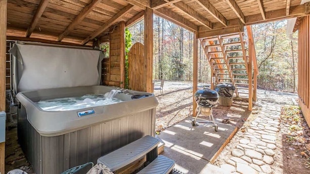 A wooden cabin with a hot tub, outdoor seating, and a stone pathway.
