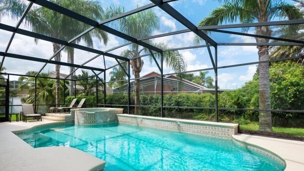 A swimming pool with a glass enclosure, surrounded by palm trees and a view of a residential area. - Ly230329 - Arcadia Estates - 7 Bed 6.5 Baths Villa (Kissimmee)