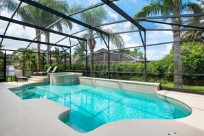 Une piscine dotée d’une structure en verre, entourée de palmiers et offrant une vue sur un quartier résidentiel.