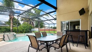 A covered outdoor area with a pool, a table with chairs, and a bar. - Ly230329 - Arcadia Estates - 7 Bed 6.5 Baths Villa (Kissimmee)