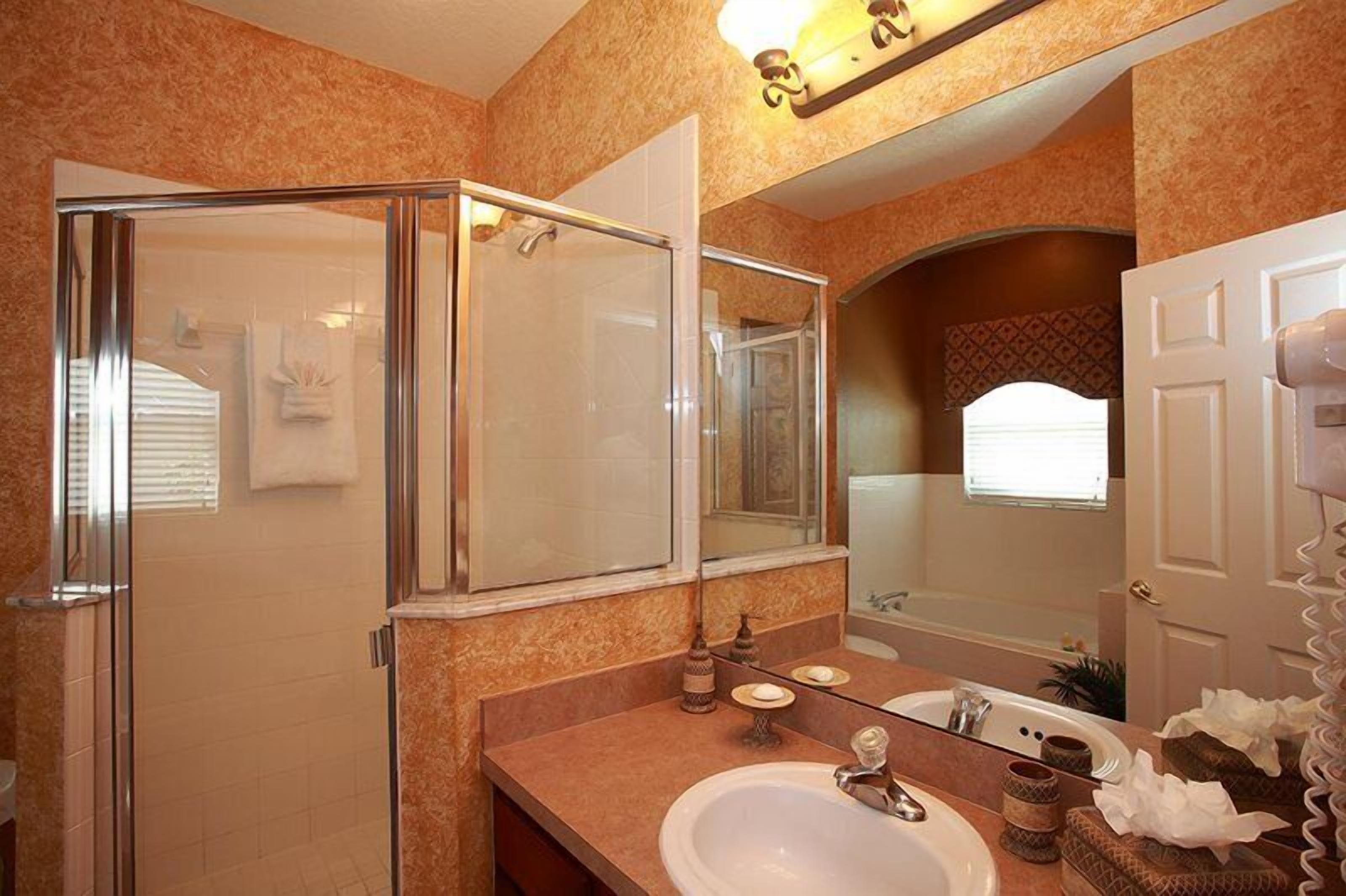 A bathroom with a glass-enclosed shower, a sink with a mirror, and a bathtub.
